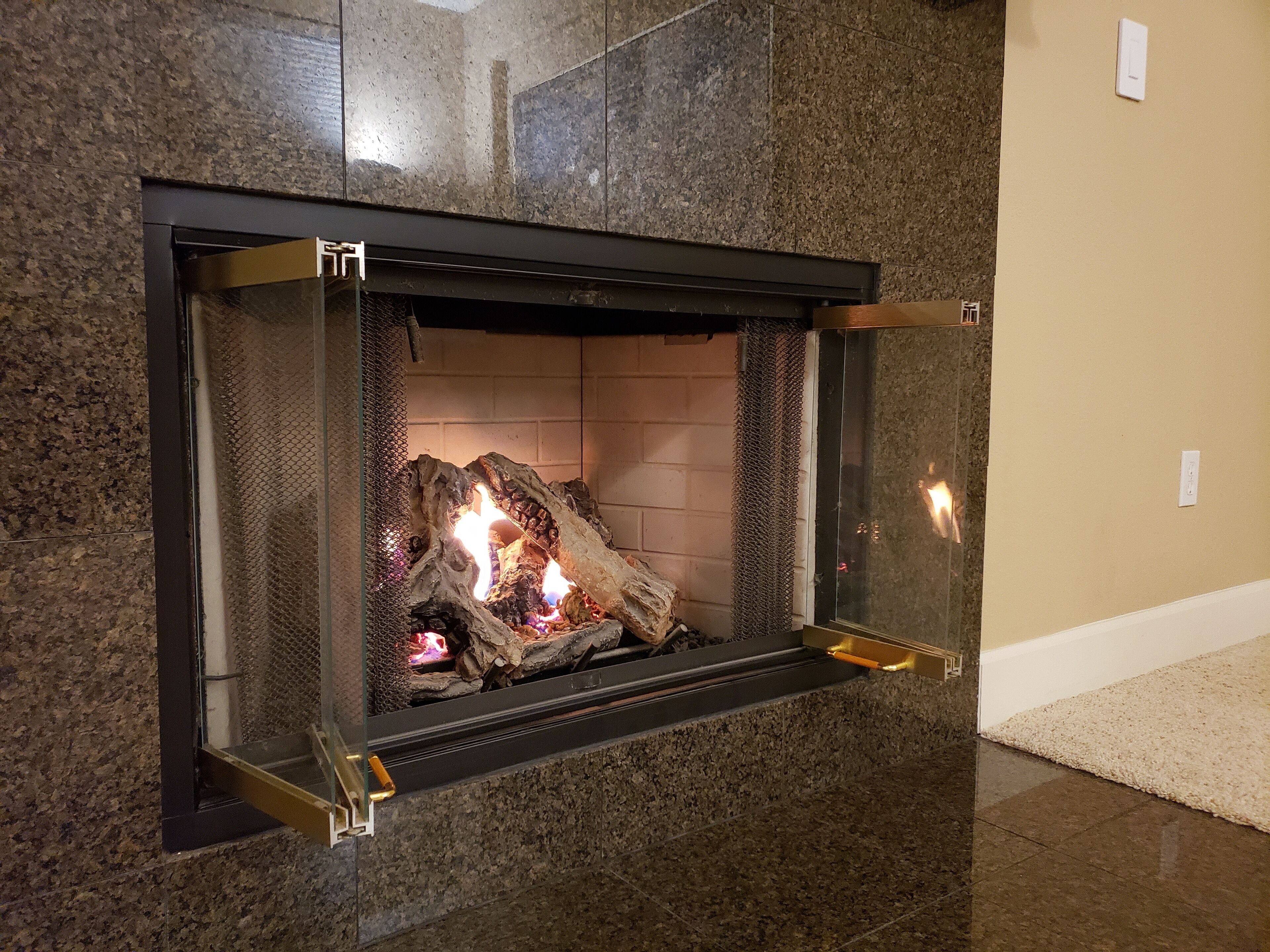 A fireplace with a stone surround and a glass front.