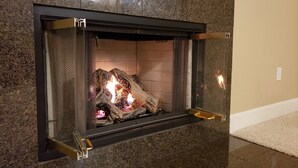 A fireplace with a stone surround and a glass front. - Tesla EV Charger Solar heated Pool & Hot Tub Near UC Davis, Med Center, Airport (West Sacramento)