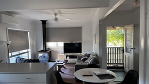 A compact living space with a kitchenette, a dining area, a sofa, and a TV. - Farmstay Cottage on the Strathbogie Tablelands. (Boho South)