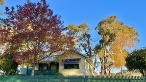 A house with a green picket fence, surrounded by trees with autumn foliage. - Farmstay Cottage on the Strathbogie Tablelands. (Boho South)