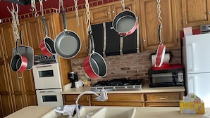 A kitchen with hanging pots, a sink, a stove, and a refrigerator.