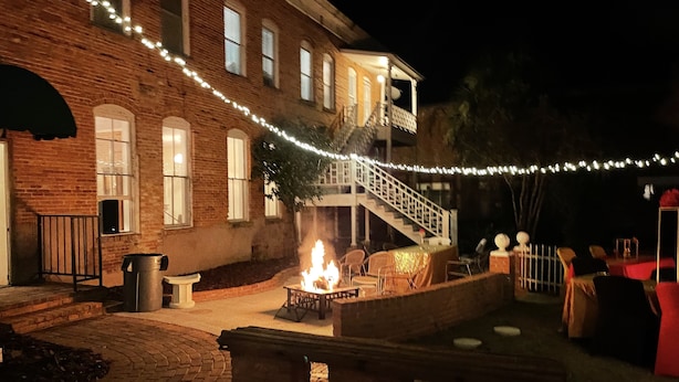 A brick building with a fire pit and outdoor seating area, decorated with string lights.