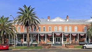 A two-story brick building with a porch decorated with red and white banners.