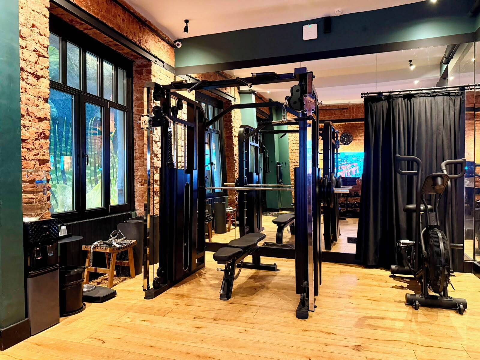 A gym with a brick wall, large windows, and various exercise equipment.
