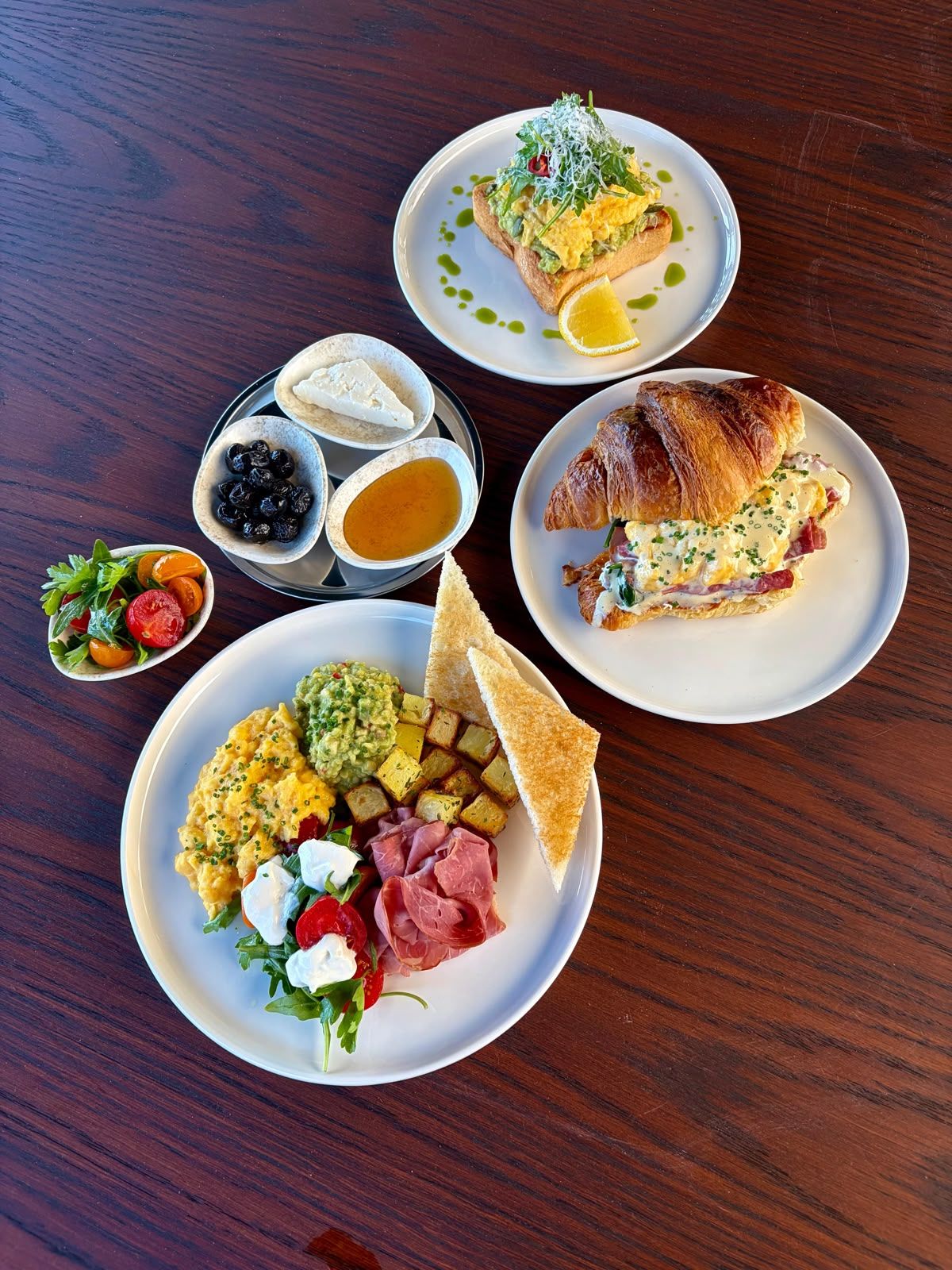 A variety of breakfast dishes on plates, including scrambled eggs, avocado, and toast.