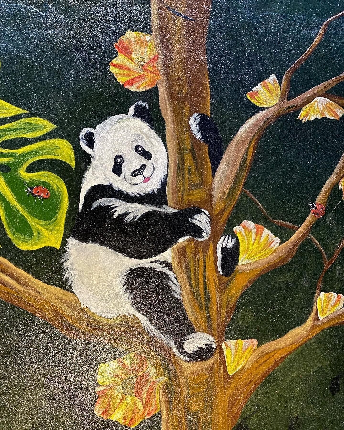 A panda climbing a tree with flowers and leaves.