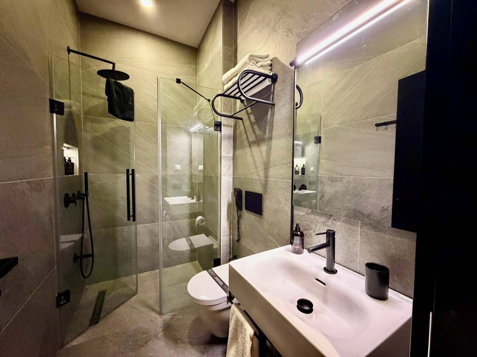 A modern bathroom with a glass-enclosed shower, a white sink, and a mirror.