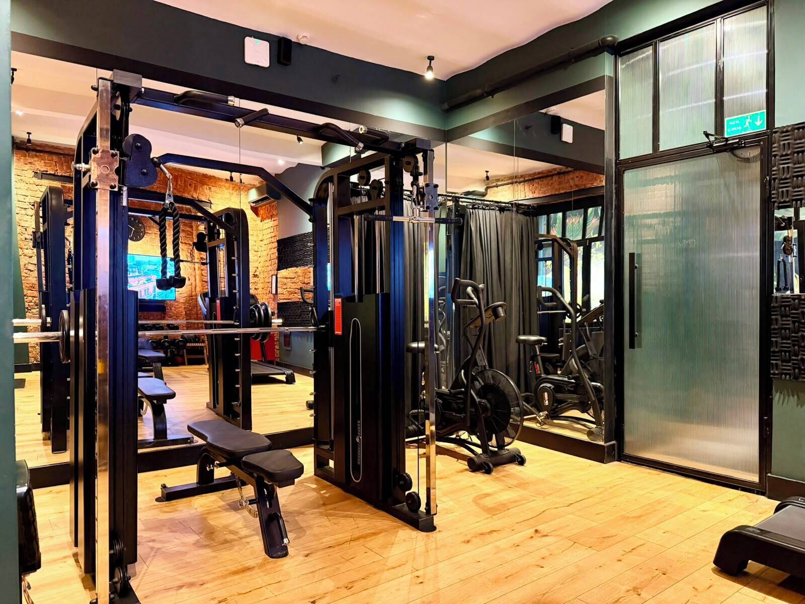 A gym with various exercise equipment, a bench, and a mirrored wall.
