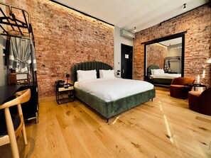 Una habitación de hotel moderna con pared de ladrillo, una cama grande, un escritorio con una silla y un espejo.