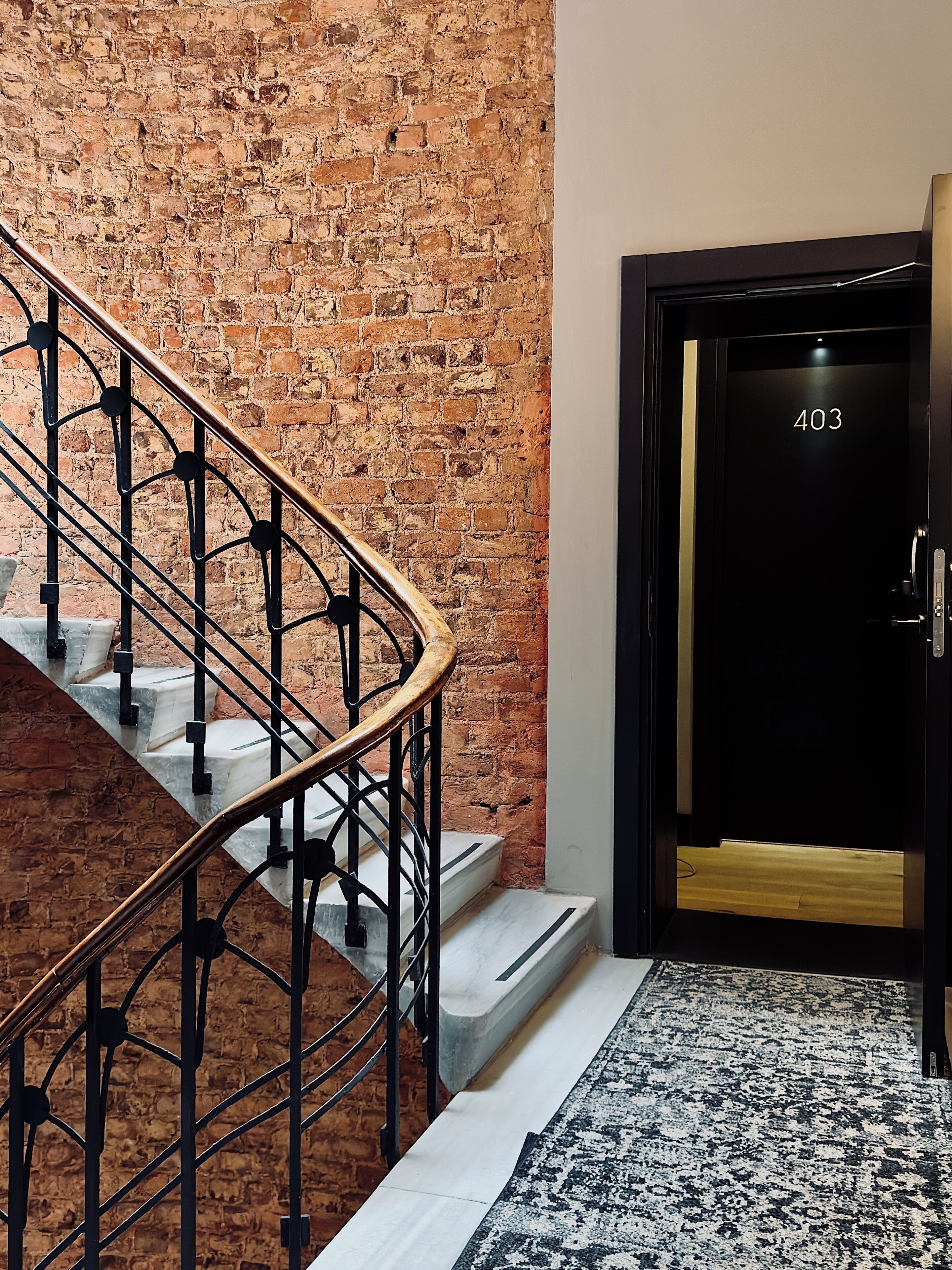 A staircase with a wrought iron railing leading to a door marked '403'.