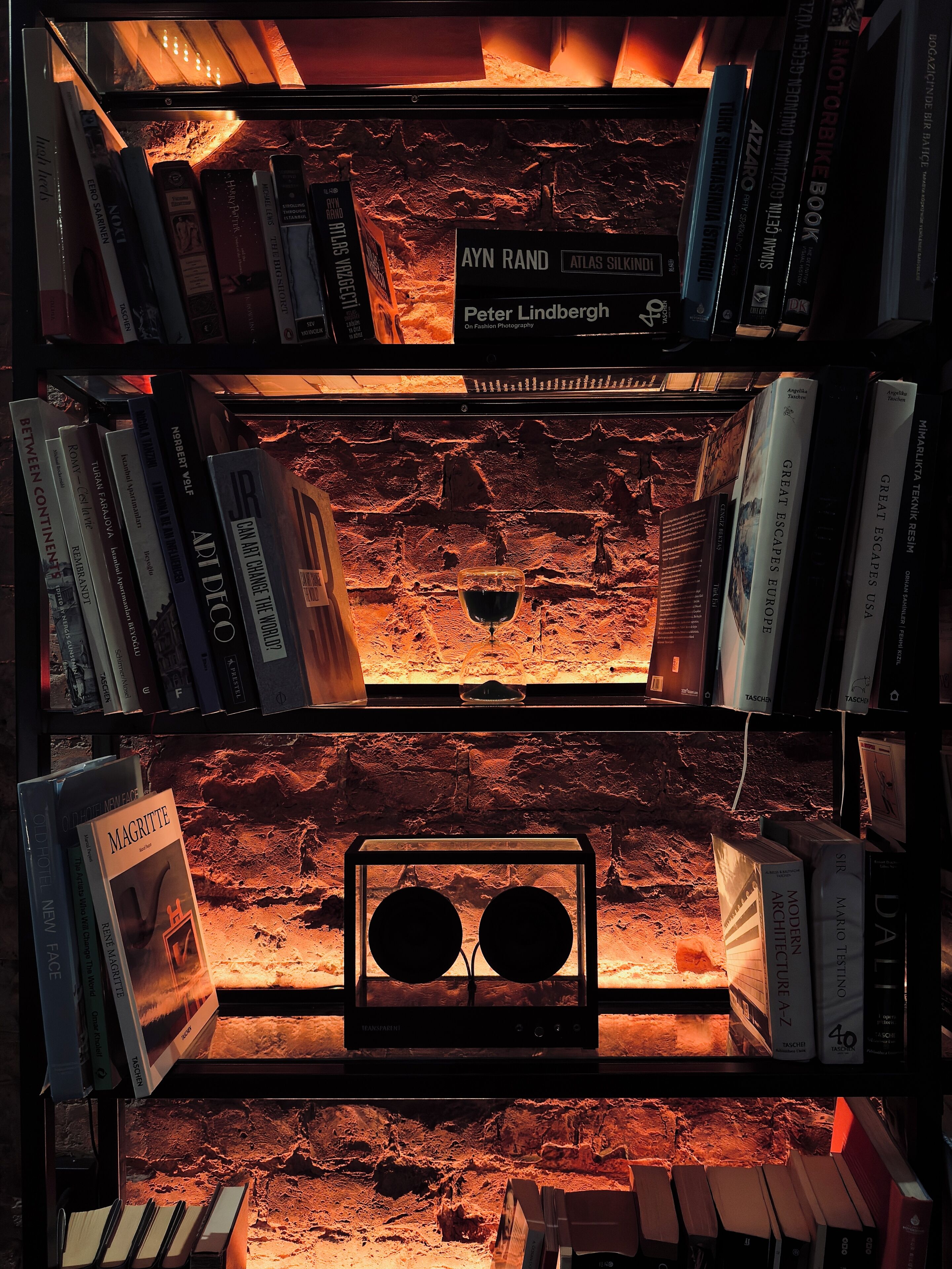 A bookshelf with books and a transparent display case.