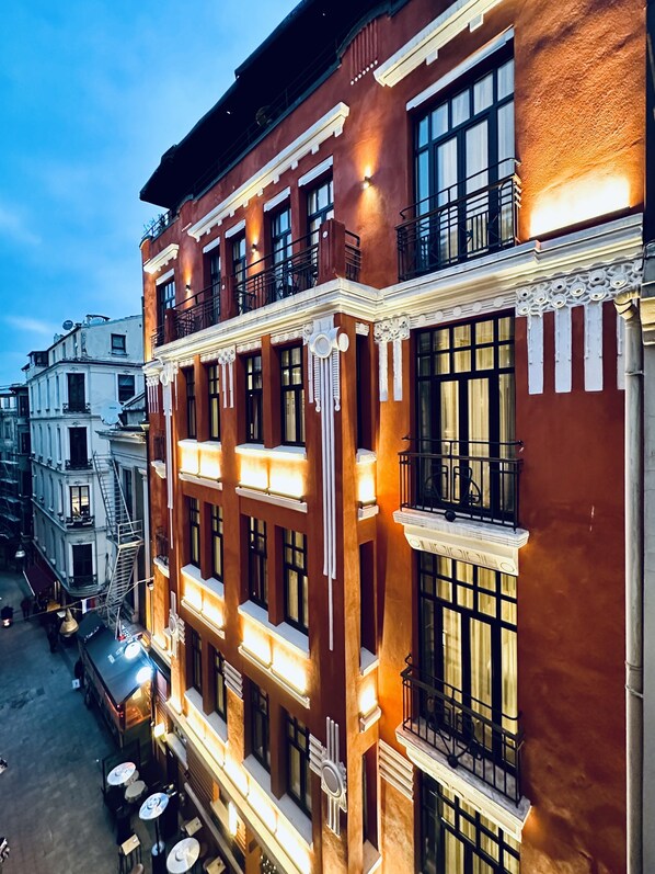 Um edifício com vários andares, varandas, janelas amplas e um café no térreo.
