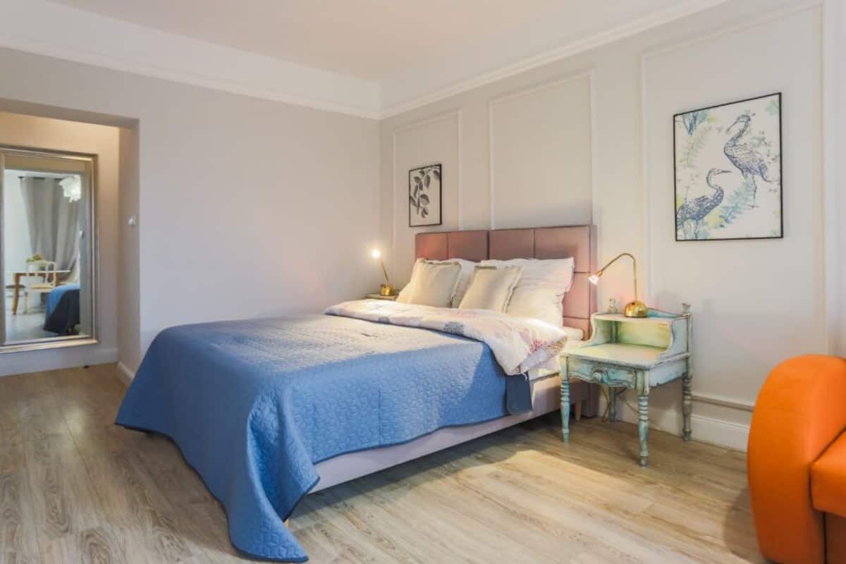 A bedroom with a bed, bedside table, and a mirror.