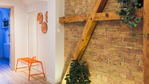 Une pièce avec un mur en briques, une poutre en bois et une plante en pot.