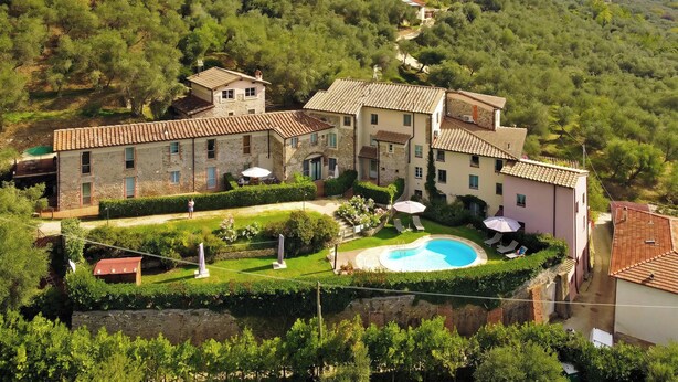 A villa with a swimming pool, surrounded by lush greenery and hills.