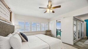 Un dormitorio con cama, ventilador de techo, ventana y vistas al exterior.