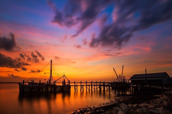 A pier with fishing boats and a building at sunset.