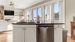 A modern kitchen with a dishwasher, a built-in oven, and a large window. - Spacious 3BR ocean-view condo, beautifully decorated! (Fernandina Beach)