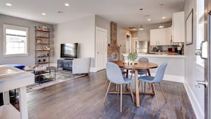 A modern living room with a TV, seating, and a dining area. - Charming 3BR Uptown home with fenced yard. Walk to Magazine St, near streetcar & FQ. (New Orleans)