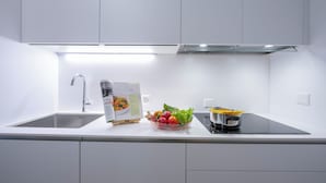 A modern kitchen with a stainless steel sink, a bowl of fresh vegetables, and a cooking pot. - Boutique Apartment 3 (Lugano)