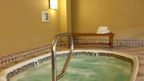 A hot tub with a metal ladder, a bench with towels, and a tiled border. - ON THE STRIP! | Classic Comfort - 2 Bedroom Condo (Las Vegas)