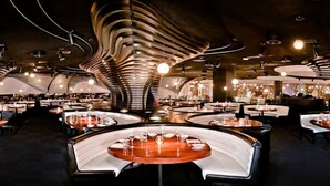 A modern restaurant with curved seating and a unique ceiling design. - ON THE STRIP! | Classic Comfort - 2 Bedroom Condo (Las Vegas)