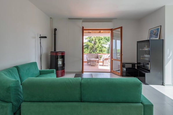 A modern living room with a green sofa, a fireplace, and a view of an outdoor patio.