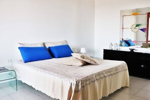 A bedroom with a bed, a bedside table, a dresser, and a mirror.