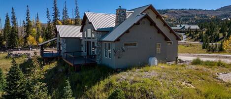 A two-story house with a stone facade, a balcony, and a metal roof.