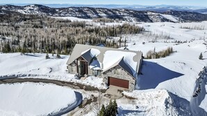 Une maison de montagne recouverte de neige, avec une façade en pierre et un garage.