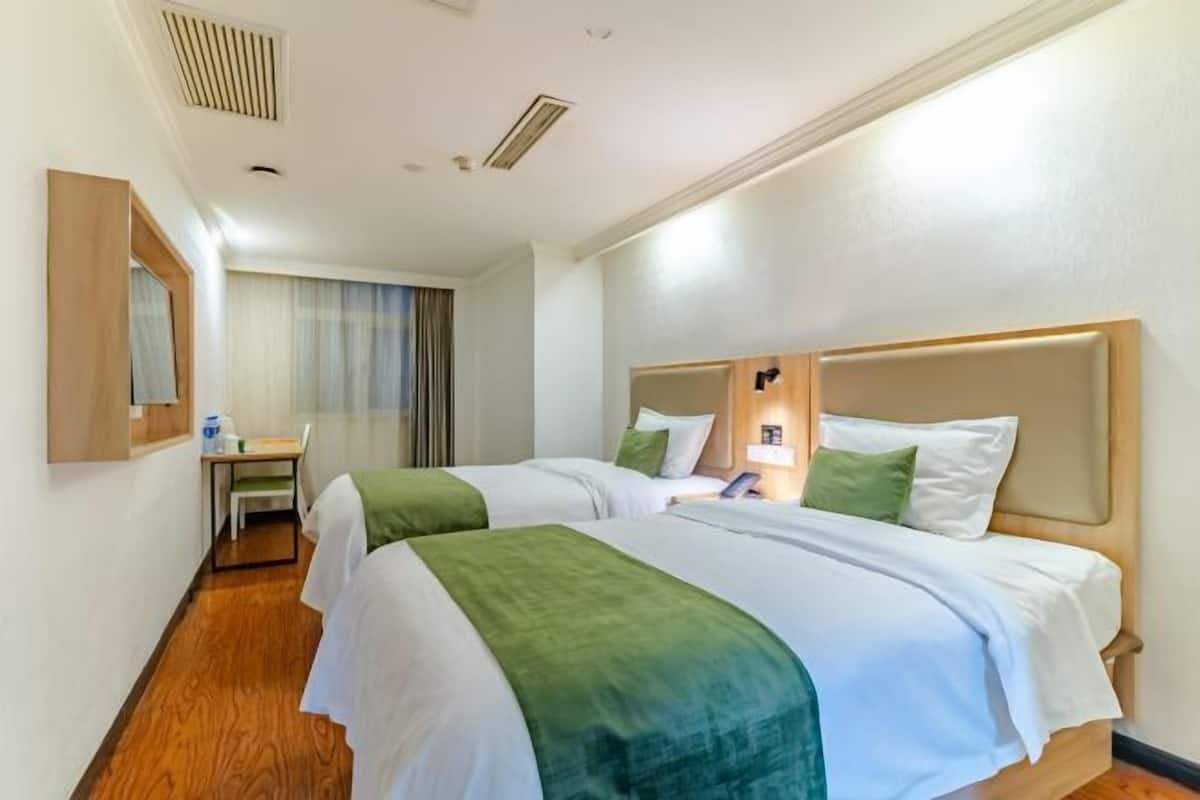 A hotel room with two beds, a desk, and a chair.