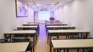 A conference room with tables and chairs arranged in rows, a projector screen at the front, and a framed artwork on the wall. - GreenTree Inn (Hefei Datang International Honggang Metro Station) (Hefei)