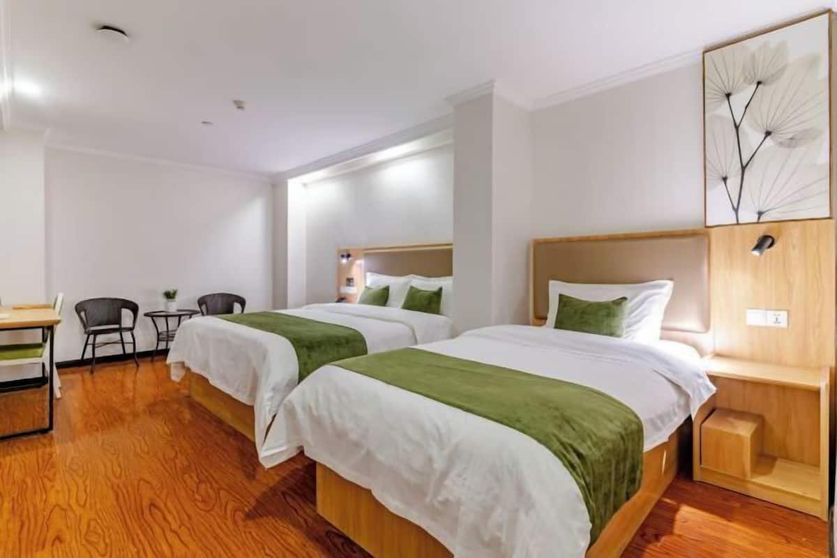 A hotel room with two beds, a desk, and chairs.