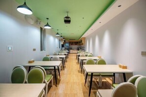 A modern dining area with tables and chairs arranged in rows, a green ceiling, and pendant lighting. - GreenTree Inn (Hefei Datang International Honggang Metro Station) (Hefei)