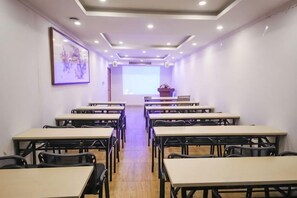 A conference room with multiple tables and chairs arranged in rows, a projector screen at the front, and a framed artwork on the wall. - GreenTree Inn (Hefei Datang International Honggang Metro Station) (Hefei)