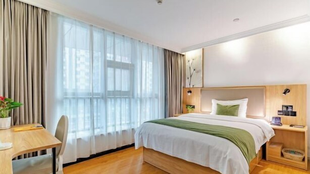 A modern hotel room with a wooden bed, a desk, and a large window with sheer curtains. - GreenTree Inn (Hefei Datang International Honggang Metro Station) (Hefei)