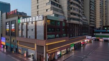 A modern hotel with a prominent sign for a restaurant, multiple floors, and a busy street in the background.