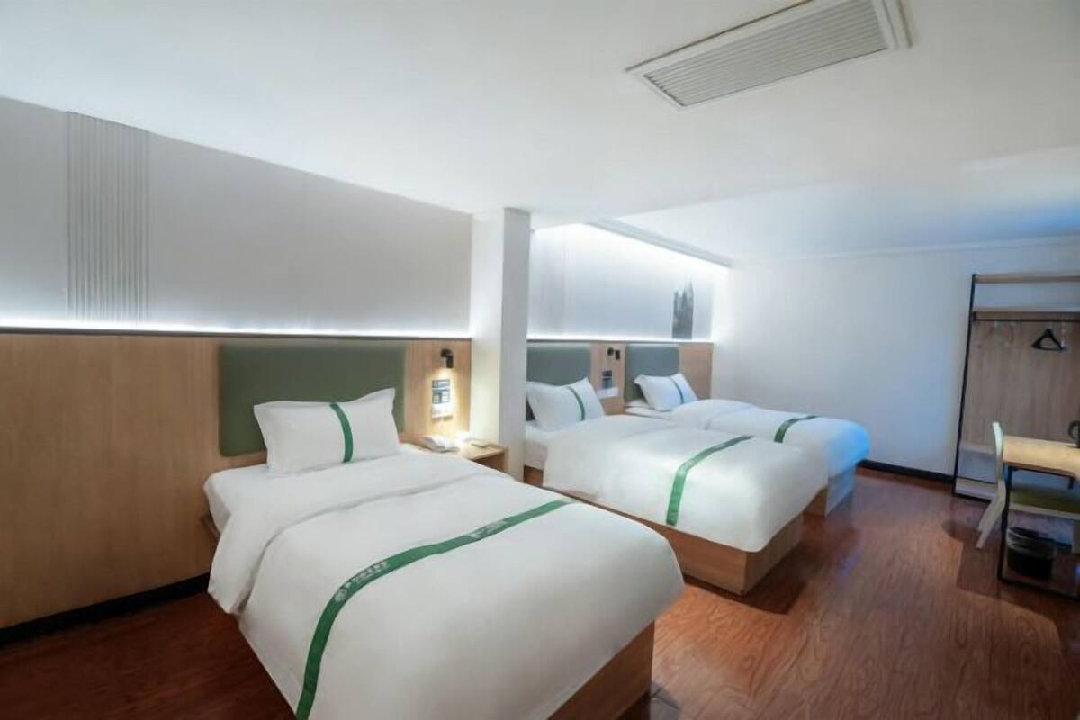 A hotel room with two beds, a desk, and a wardrobe.