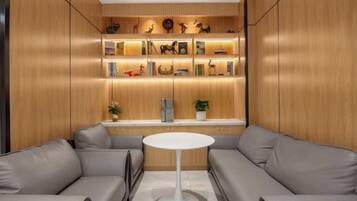 A modern interior with a sofa set, a central white table, and a wooden shelving unit with decorative items.