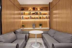 A modern interior with a sofa set, a central white table, and a wooden shelving unit with decorative items. - GreenTree Inn (Hefei Datang International Honggang Metro Station) (Hefei)