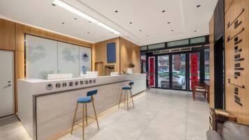 A reception area with a counter, two blue bar stools, and a wooden panel wall.