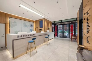 A reception area with a counter, two blue bar stools, and a wooden panel wall. - GreenTree Inn (Hefei Datang International Honggang Metro Station) (Hefei)