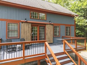 A two-story building with a deck, outdoor seating, and a staircase.
