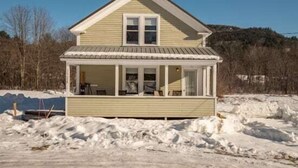 A two-story house with a covered porch, a front door, and a small front yard. - Sunday River Getaway (Newry)