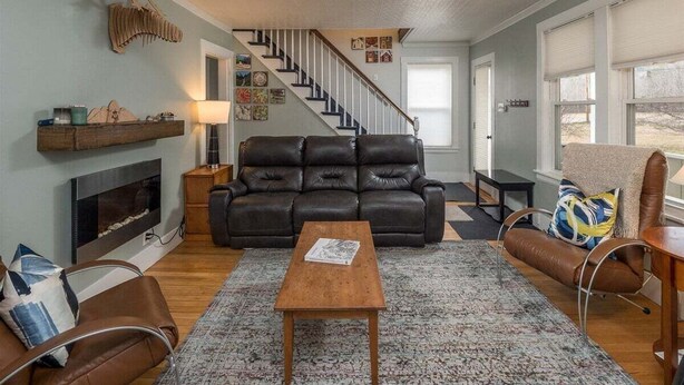 A living room with a fireplace, a black leather sofa, a wooden coffee table, and a brown leather armchair. - Sunday River Getaway (Newry)