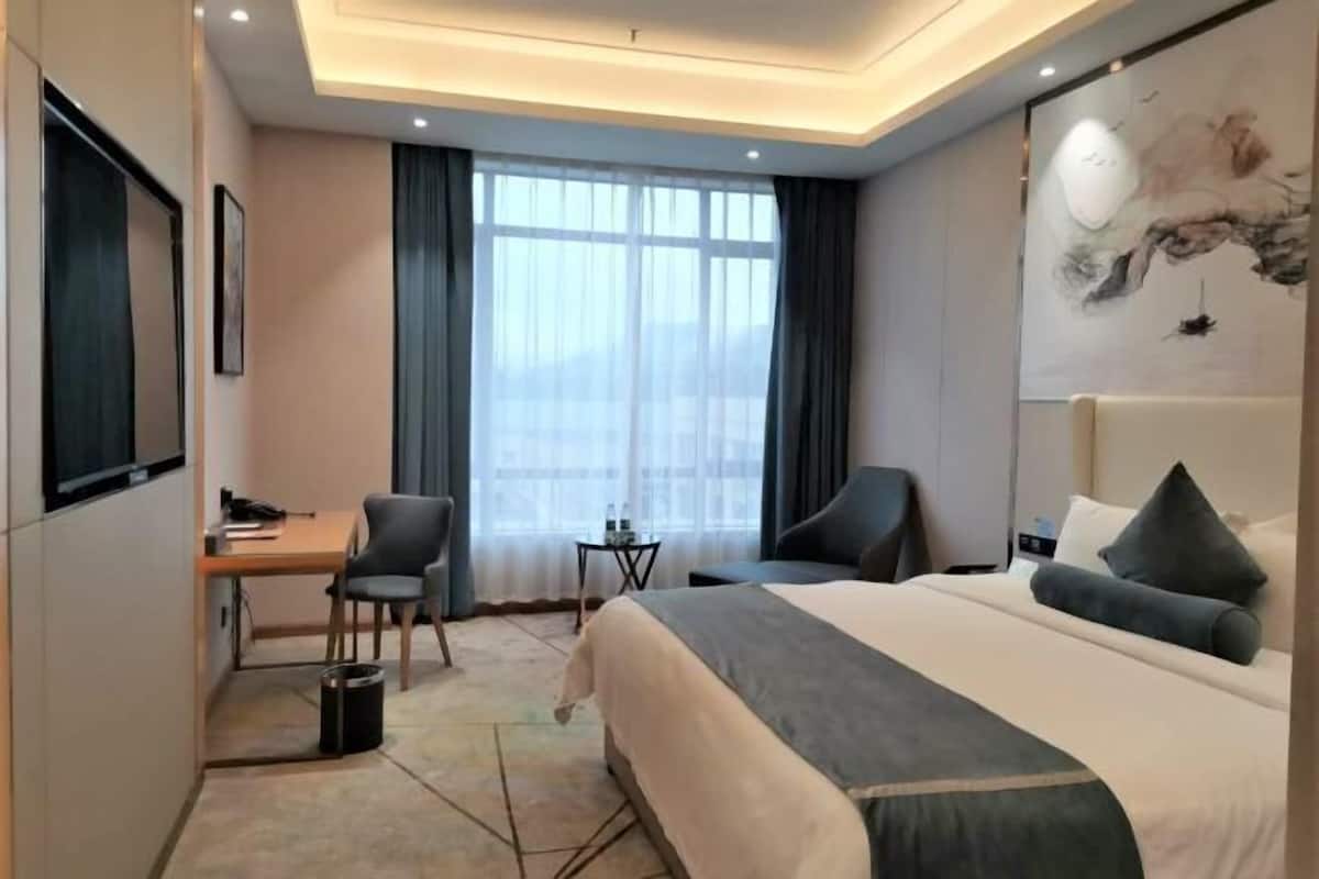 A hotel room with a bed, desk, chairs, and a small table.