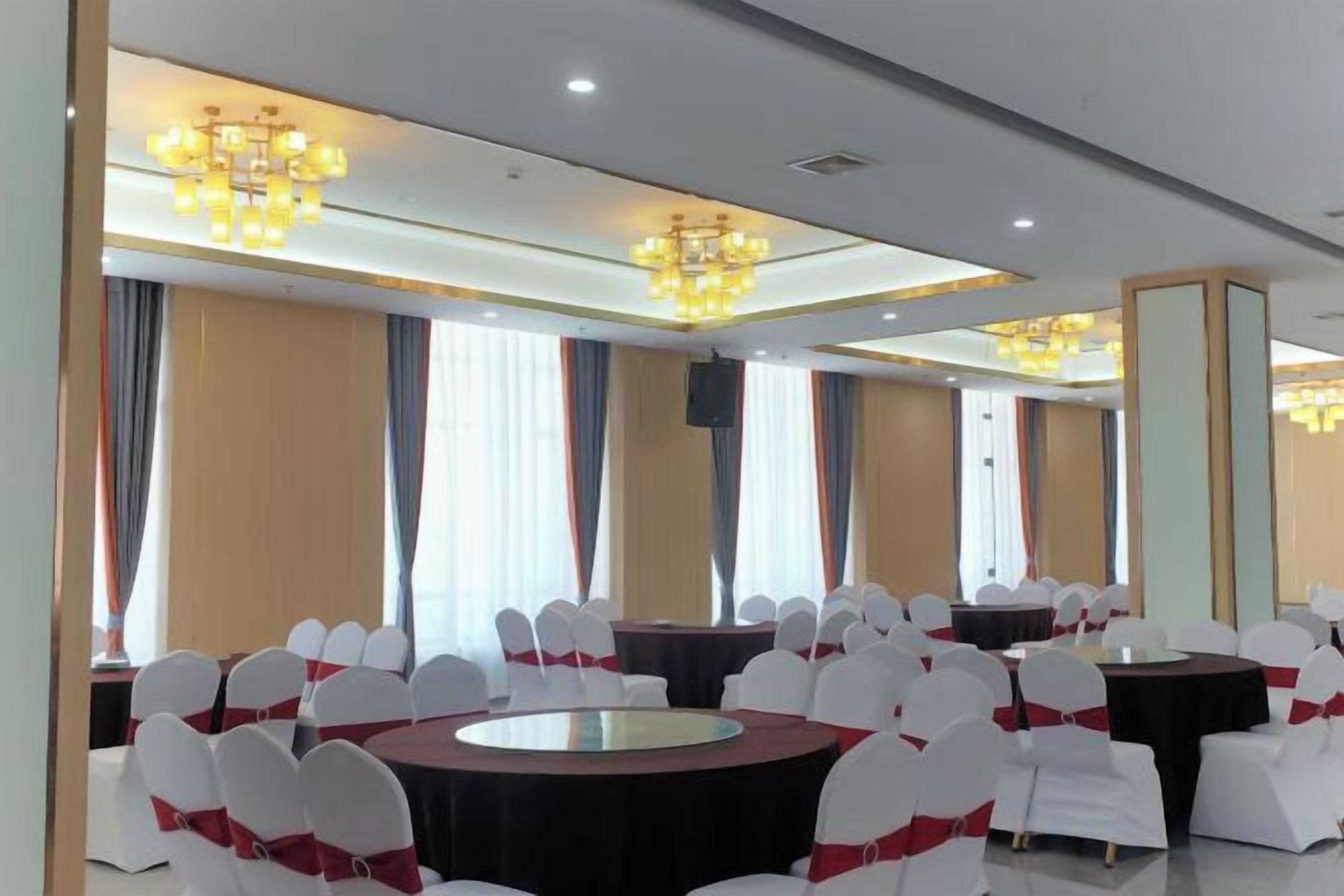 A conference room with round tables, white chairs, and chandeliers.