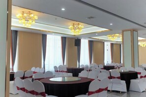 A conference room with round tables, white chairs, and chandeliers. - Xingpeng International Hotel (Huayuan)