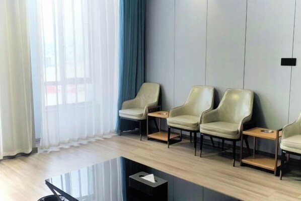 Un área de espera moderna con cuatro sillones de cuero, una mesa de vidrio y un cubo de basura pequeño.