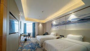 A hotel room with two beds, a desk, a chair, and a large painting on the wall. - Xingpeng International Hotel (Huayuan)